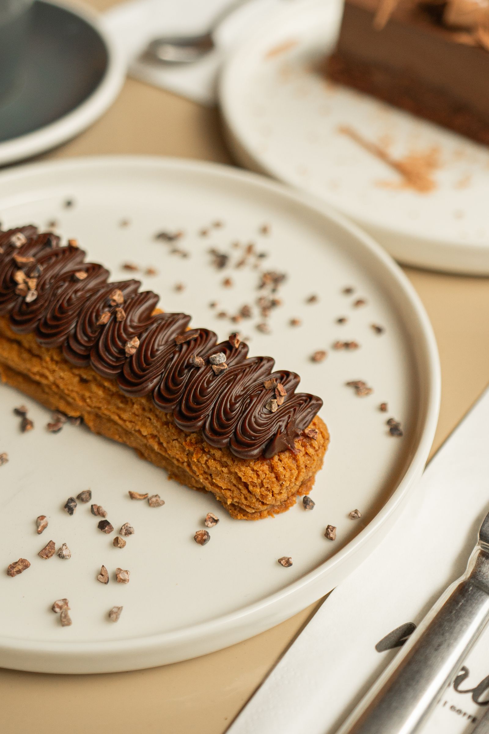 Chocolate éclair with piped ganache and cocoa nibs