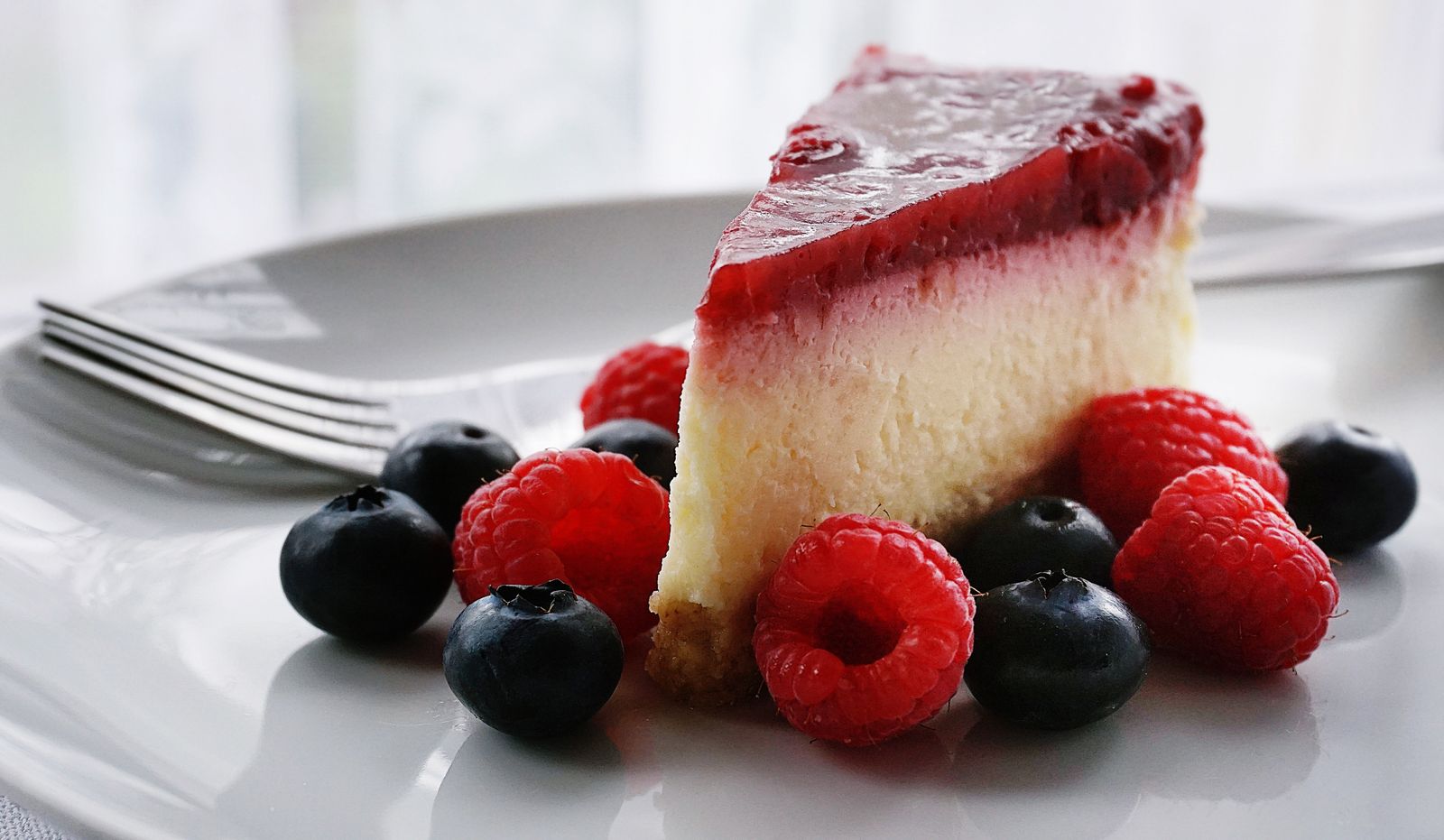 Slice of baked cheesecake with raspberries and blueberries