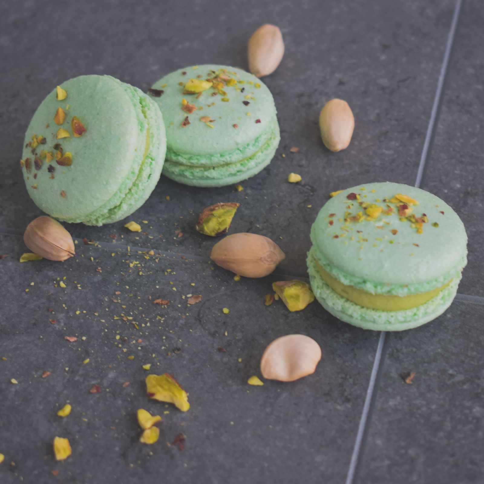 Pistachio macarons with crushed pistachio on dark slate