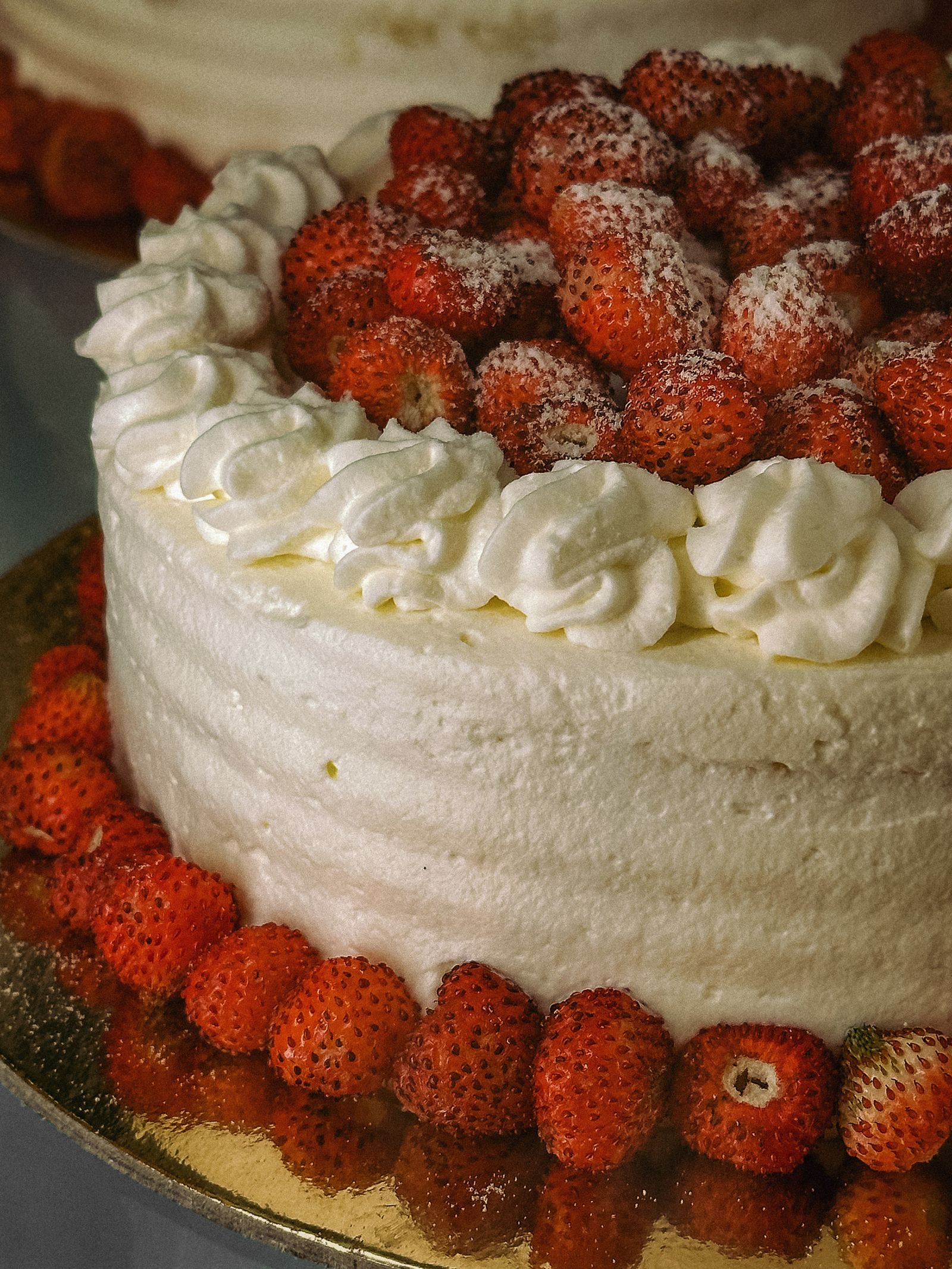 Close-up of a strawberry cream cake with whipped rosettes and wild strawberries