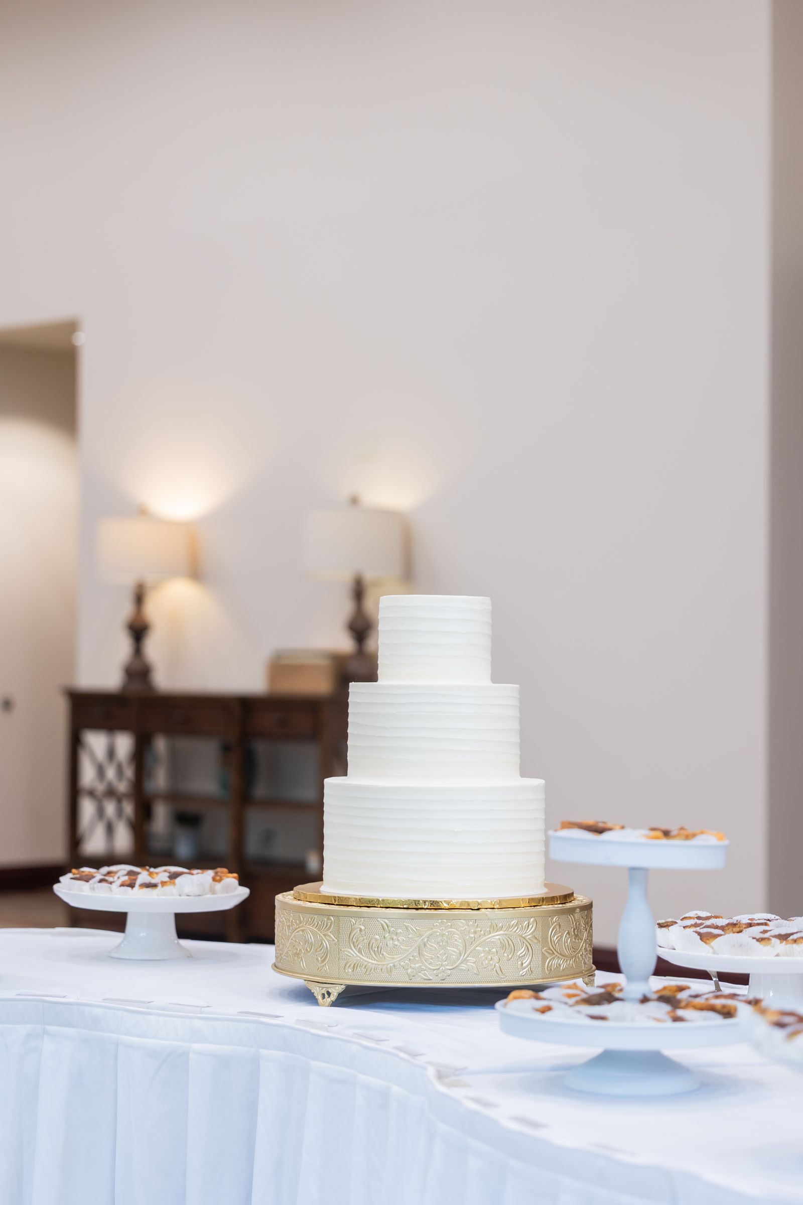 Elegant tall tiered white celebration cake on a gold stand